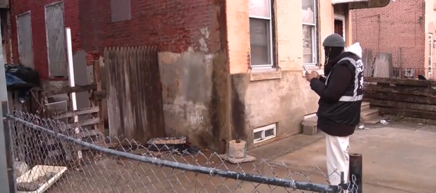 West Philadelphia CoLab Coordinator Christopher Oluwole stands in front of a neighborhood blight, capturing it on his phone using the Google Earth app on the first night of patrol. 